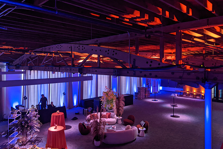 Spot lighting highlights tables and displays throughout the event space at AVENUE