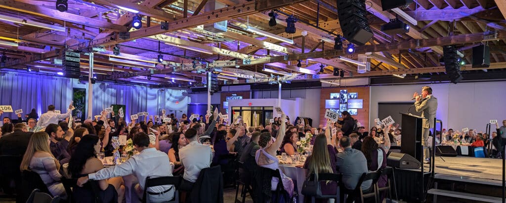 A professional lighting design and installed lighting system casts colorful beams of light across the curved wood ceiling at AVENUE