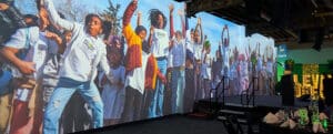 AVENUE's projection wall displays a larger than live image of children cheering and jumping