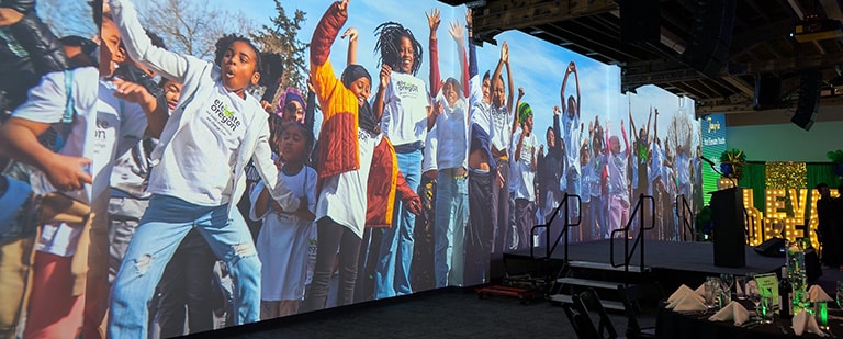 AVENUE's projection wall displays a larger than live image of children cheering and jumping