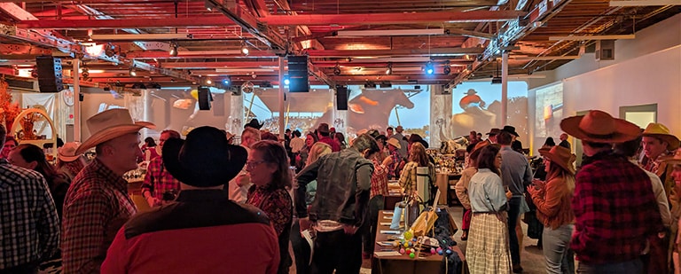 The western theme was brought to live at an event with an immersive projection of a larger-than-life rodeo. Horses run across the room on the 93-foot projection room as guests mingle before the program begins.